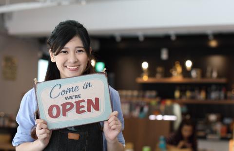 woman holding a sign saying 'we're open'